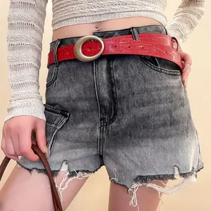 Vintage red leather belt with silver ring buckle on grey washed denim shorts