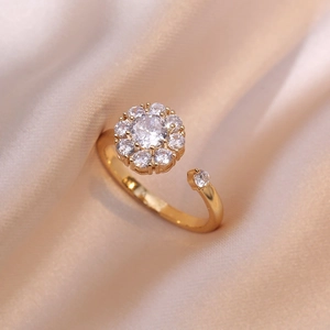 Anillo de flor dorado ajustable con circón blanco sobre fondo de seda suave