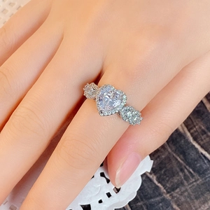 Macro shot of silver heart zircon ring with halo crystals and three-stone side accents