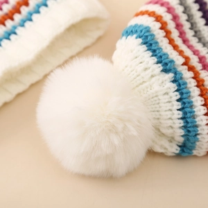 Cozy colorful striped knit hat with large white faux fur pom-pom for winter warmth