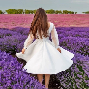 Robe de mariée courte blanche avec manches bouffantes à pois dans un champ de lavande
