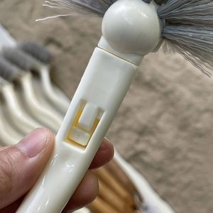 Détail de la poignée en plastique blanc avec poils gris et boucle jaune spécifique