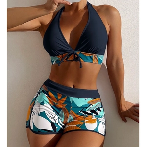 Detail of high waist boyleg bikini bottom with tropical leaf print and navy halter top