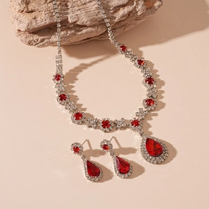 Macro shot of silver-toned red teardrop necklace and earrings set on natural stone