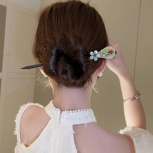 Detail of wooden hair stick with blue flower and golden fan in a classic bun