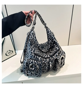 Detail of leopard print tote bag featuring silver metal rings and multiple outer pockets