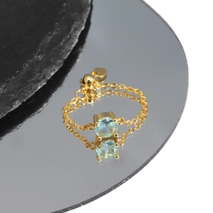 Detailed macro view of gold chain ring with blue zircon and adjustable heart charm