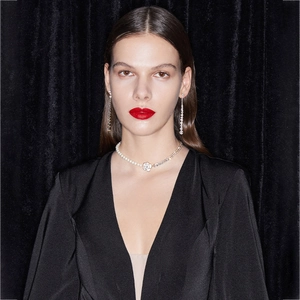 Détail de collier perle camélia et boucles d'oreilles franges sur mannequin sur velours