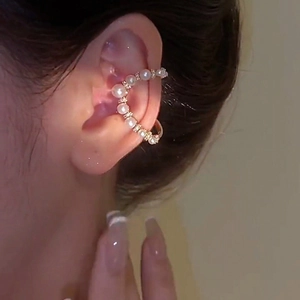 Detail of elegant gold ear cuff featuring white pearls and shimmering rhinestones
