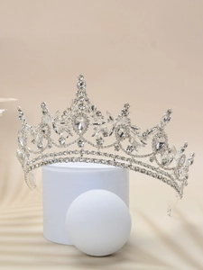 Detailed view of a silver bridal crown with sparkling rhinestones on a white pedestal