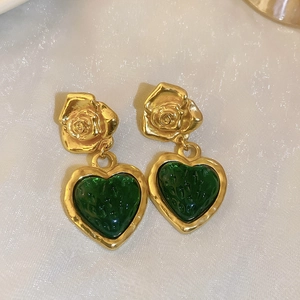 Detail of vintage gold earrings with rose studs and green resin heart pendants
