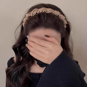 Detail of twisted champagne satin headband worn by a model for a voluminous hairstyle look