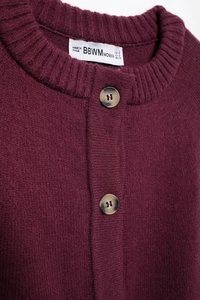 Detail of round neckline and amber buttons on this burgundy knit cardigan