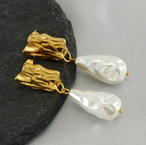 Macro detail of irregular gold metal earrings with baroque style drop pearls