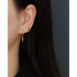 Detail of gold geometric earrings with black stones worn on earlobe and cartilage
