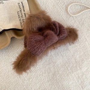 Detail shot of a brown plush bow hair claw clip on textured fabric background
