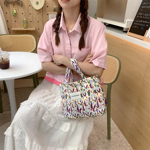 Détail d'un sac à main en toile à fleurs avec tulipes mauves dans un café en plein air