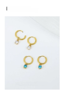 Detailed macro view of gold circular drop earrings with white and blue zircon pendants