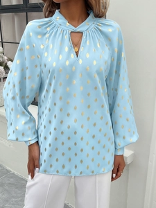 Detailed view of women's light blue shirt with gold polka dots and lantern sleeves