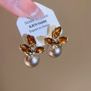 Close-up of vintage flower pearl earrings featuring amber enamel and gold plating