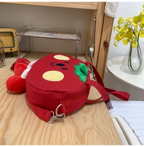 Detail of red cartoon canvas bag with yellow face embroidery and adjustable green strap