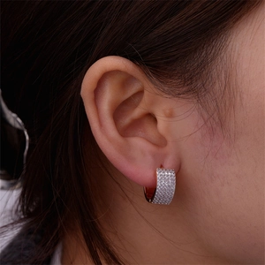 Close-up of heart-shaped U-shaped earring with sparkling diamonds on female model