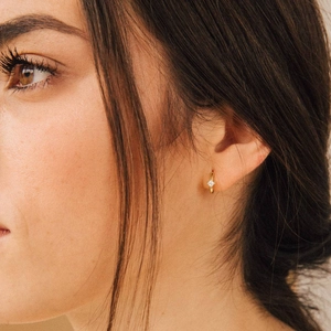 Classic gold-plated star huggie earrings with zircon stone on model's ear