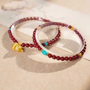Detail of cinnabar bead bracelets featuring a golden gourd charm and turquoise accents