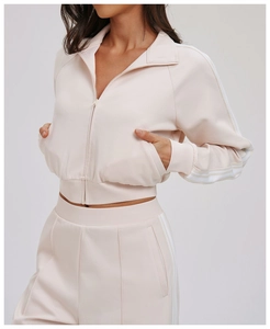 Detail view of pink jacket sleeve and pants showing three white stripes and ribbed cuff