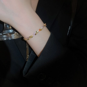 Detailed view of colorful rhinestone bracelet with adjustable gold chain on a wrist
