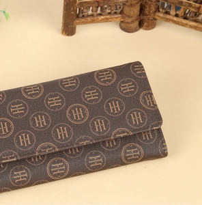 Close-up of deep brown leather wallet with patterned monogram and smooth zipper texture