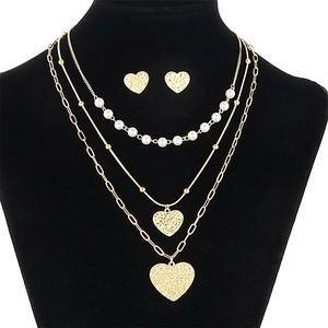 Layered gold necklace set with pearls and hammered heart pendants on display