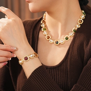 Détail d'un ensemble de bijoux vintage dorés avec perles et pierres précieuses vertes