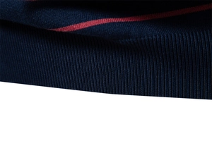 Macro detail of navy blue knit sweater featuring a red stripe and ribbed hem texture