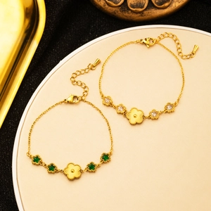 Detailed close-up of 18K gold plated flower and star bracelets on a beige display stand