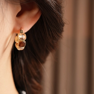Detailed macro view of vintage gold U-shaped earrings with gradient square rhinestones