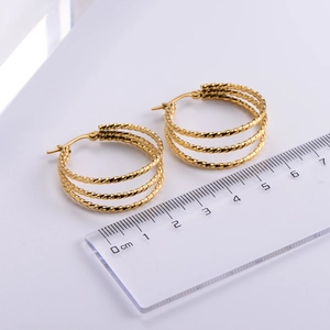 Detailed view of golden twisted rope hoop earrings with a ruler showing size measurement