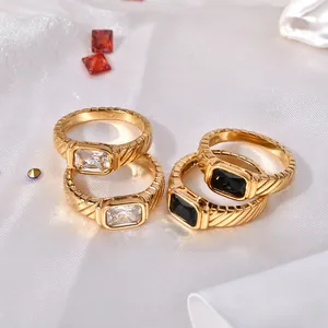 Gold titanium steel rings with black and white zircon stones on white silk background