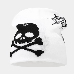 Detail of white knit beanie with black skull crossbones and spider web pattern