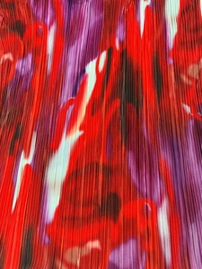Macro shot of fine vertical pleats and artistic abstract floral print on red dress fabric