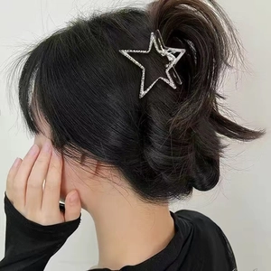 Silver alloy star-shaped hair claw clip with rhinestones worn on a woman's hair