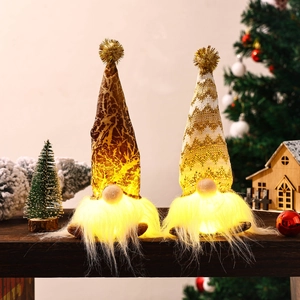 Pair of glowing Christmas gnomes on wooden surface with warm LED lights and cozy holiday decor