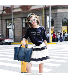 Borsa tote in pelle blu scuro abbinata a una gonna a pieghe in un contesto urbano