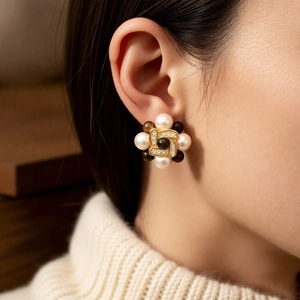 Detail view of vintage flower cluster earrings with pearls and rhinestones on a model