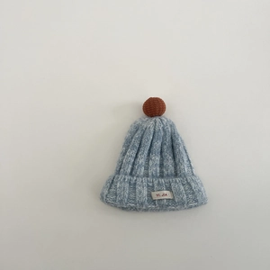 Detailaufnahme der weichen blauen Strickmütze mit braunem Bommel und Markenetikett