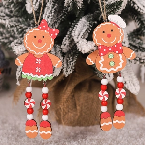 Detail of wooden gingerbread couple ornaments hanging on a snowy Christmas tree branch
