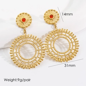 Close-up of bohemian gold titanium earrings with wavy texture and ruby stone inlays