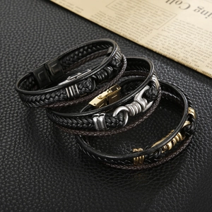 Close-up of stacked black and brown woven leather bracelets with stainless steel clasps