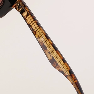 Macro detail of tortoiseshell acetate temple with engraved gold metal core inlay