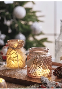 Close-up of amber glass candle holders with metal pendants and tassels for Christmas decor